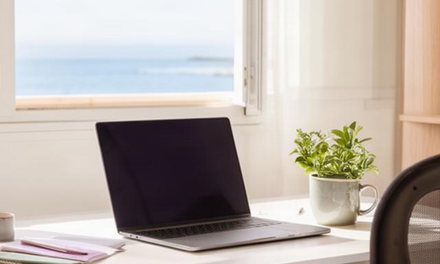 Espacio de trabajo con portátil junto a una ventana luminosa en Vinaròs